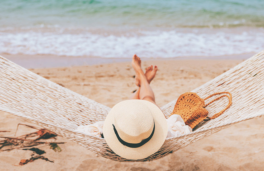 A businesswoman relaxes on a beach because her business is secure with Backup and Disaster Recovery are taken care of by Symsafe.